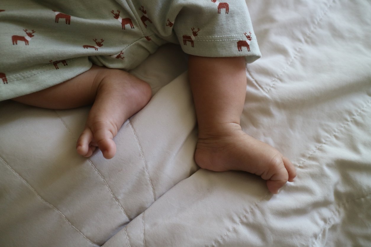 uma foto de pés fofos de um bebê recém-nascido em um colchão branco