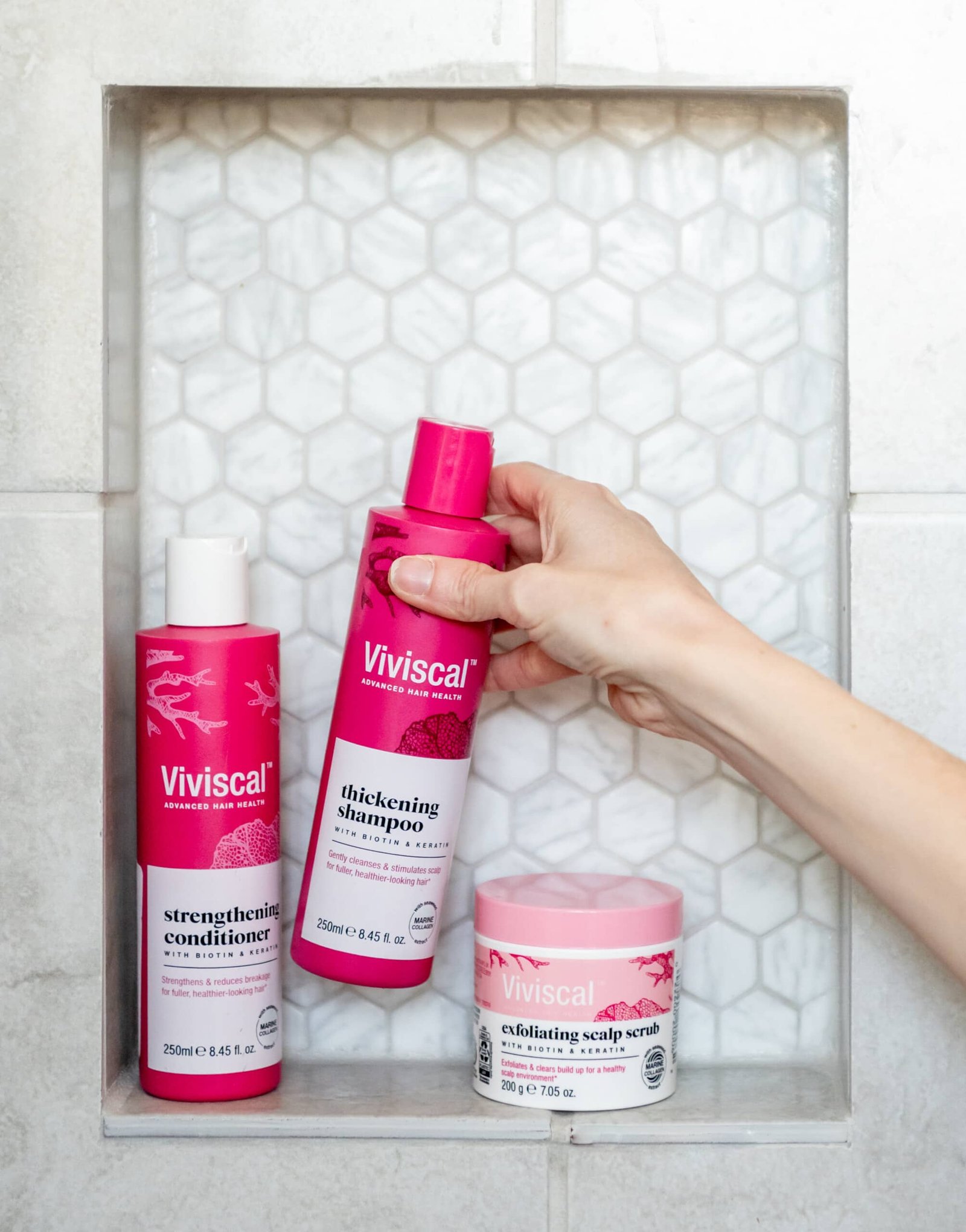 Shampoo, condicionador e esfoliante Viviscal no parapeito do banheiro