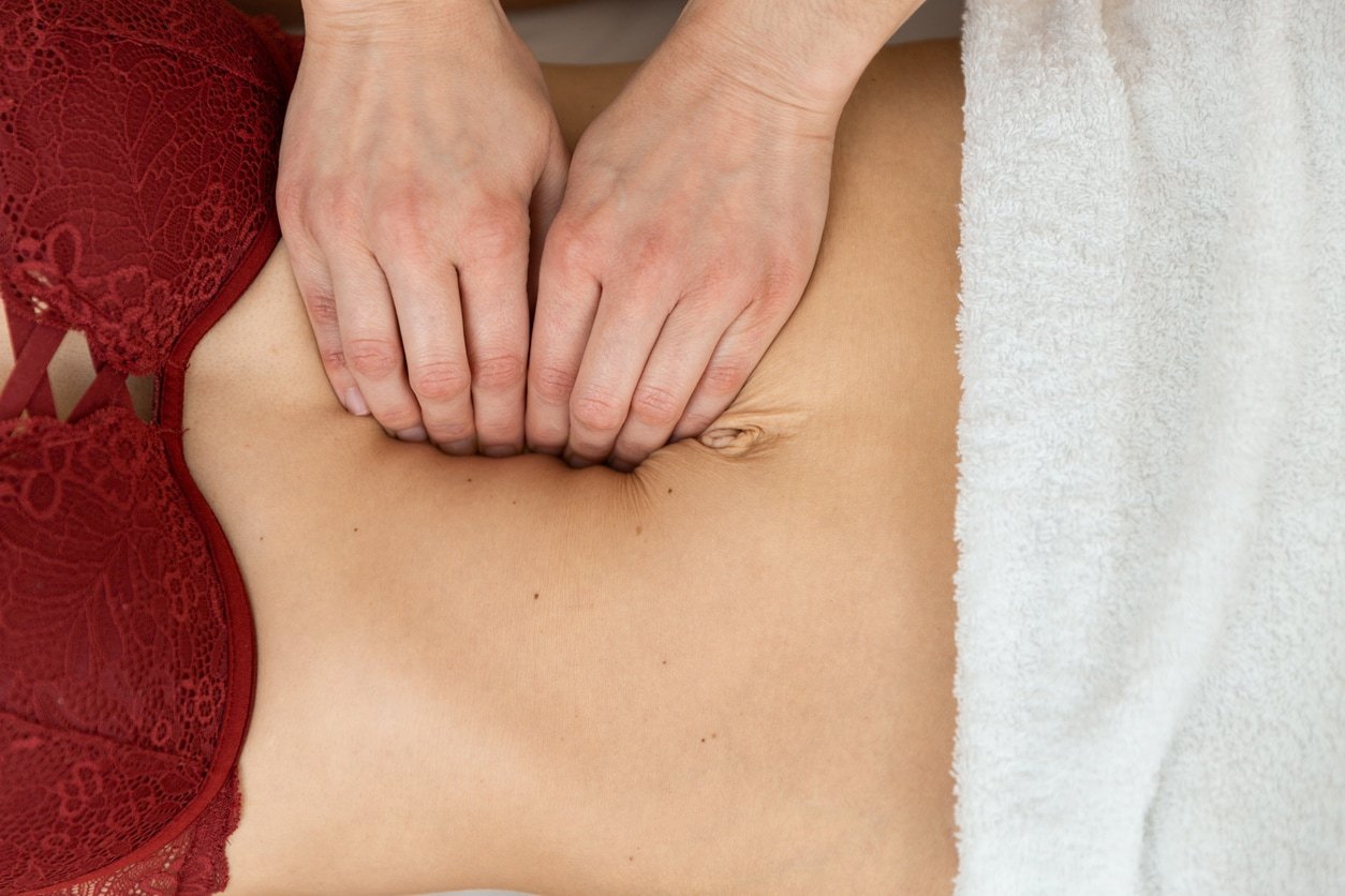 Top view of an unrecognizazble physiotherapist checking diastasis recti on belly of postpartum woman.