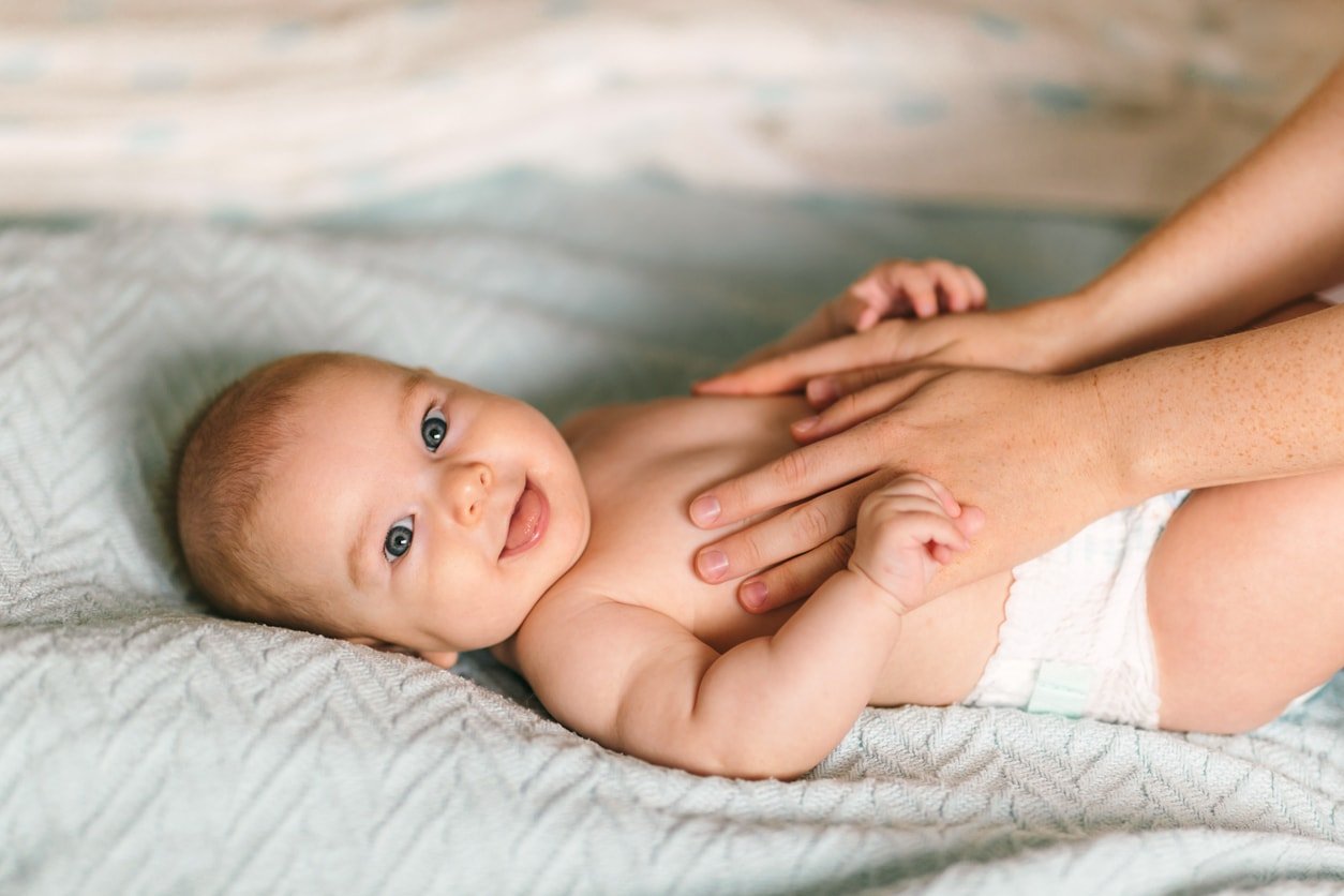 Massagem para o bebê.  Bebê de quatro meses sorrindo fazendo ginástica
