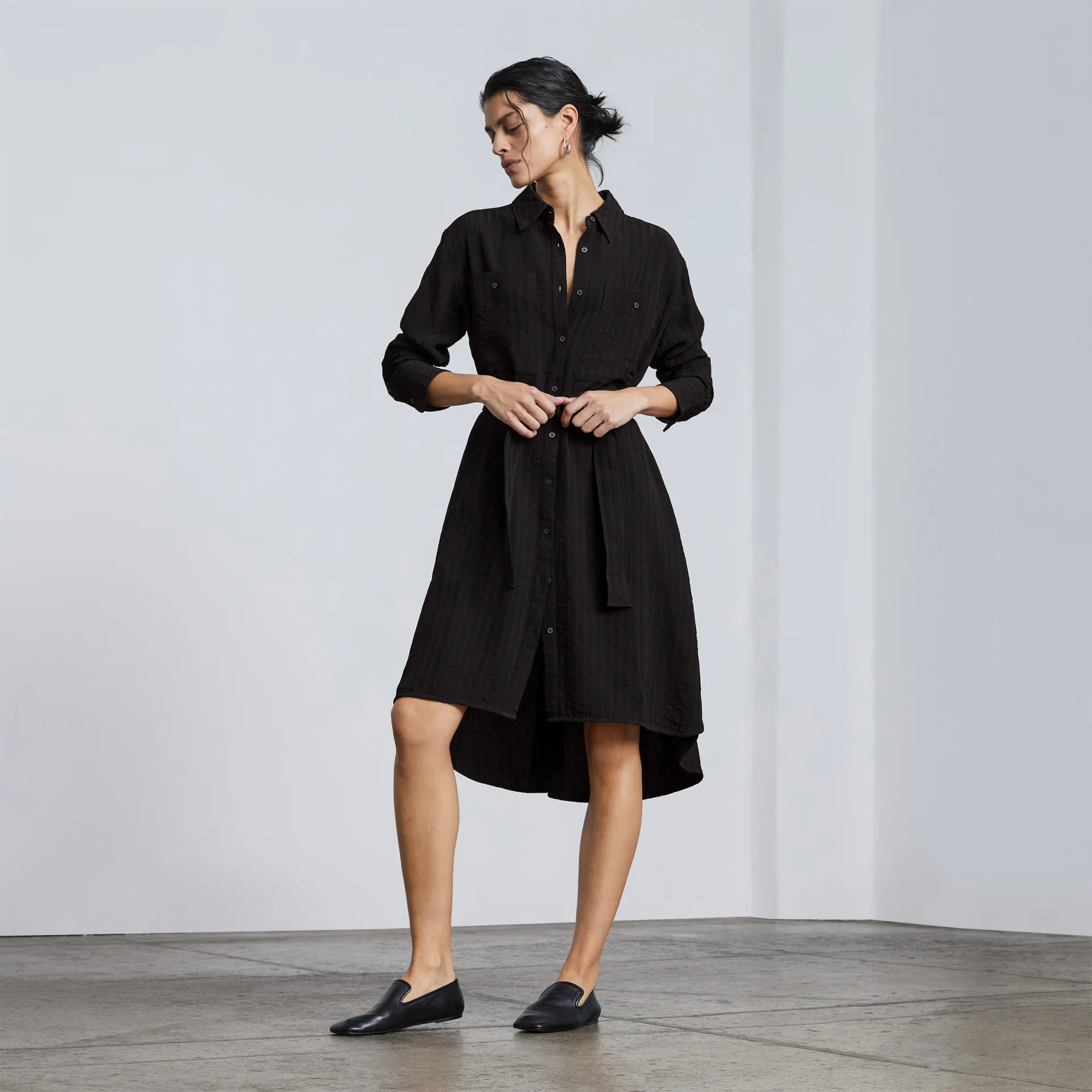 Mulher com vestido curto de camisa preta com botões 