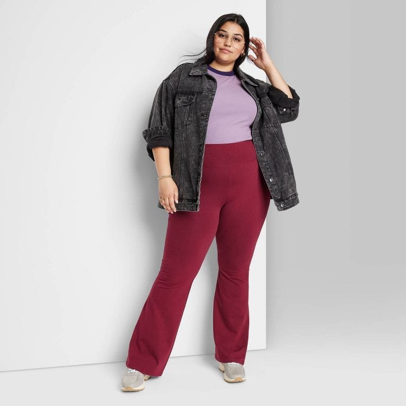 Mulher com legging vermelha, camisa roxa e jaqueta jeans preta