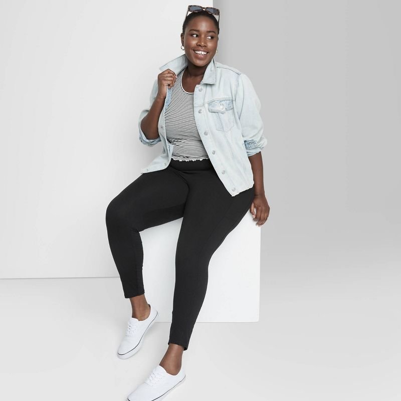 Mulher de legging preta com camisa listrada e jaqueta jeans azul 