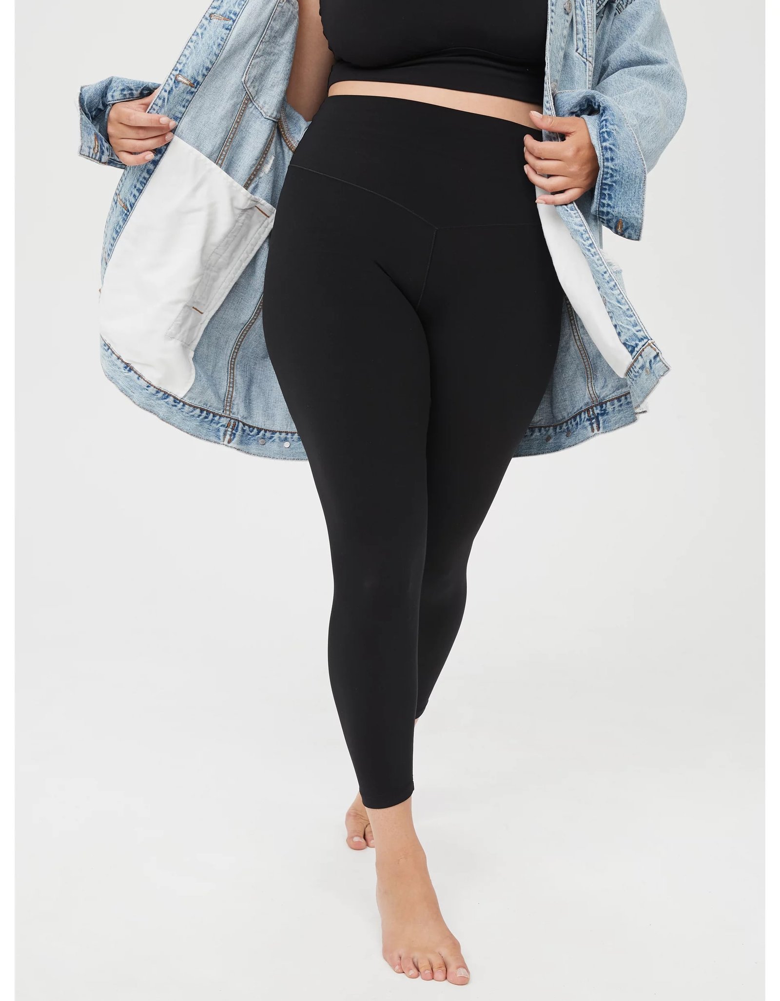 Mulher de legging preta e blusa combinando com jaqueta jeans 