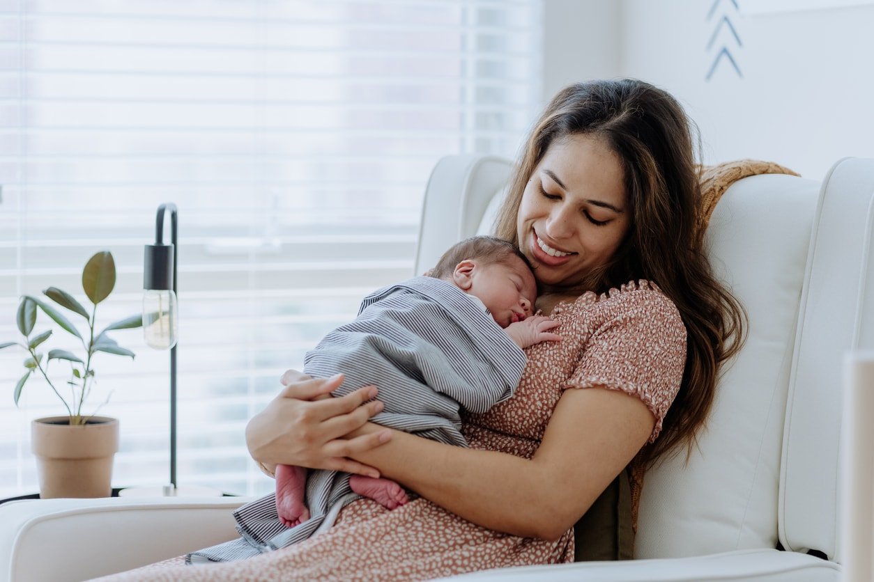 Mother holding her baby boy sitting in a glider in the nursery room