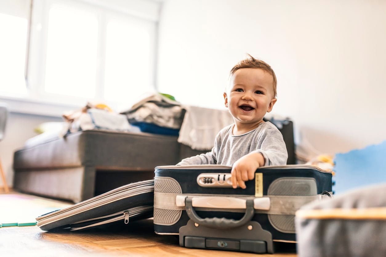 Adorável menino na mala se divertindo.  Foto de adorável menino caucasiano na mala se divertindo no quarto de hotel, se preparando para viajar.  Viagem conceitual.  um menino engraçado feliz com mala.