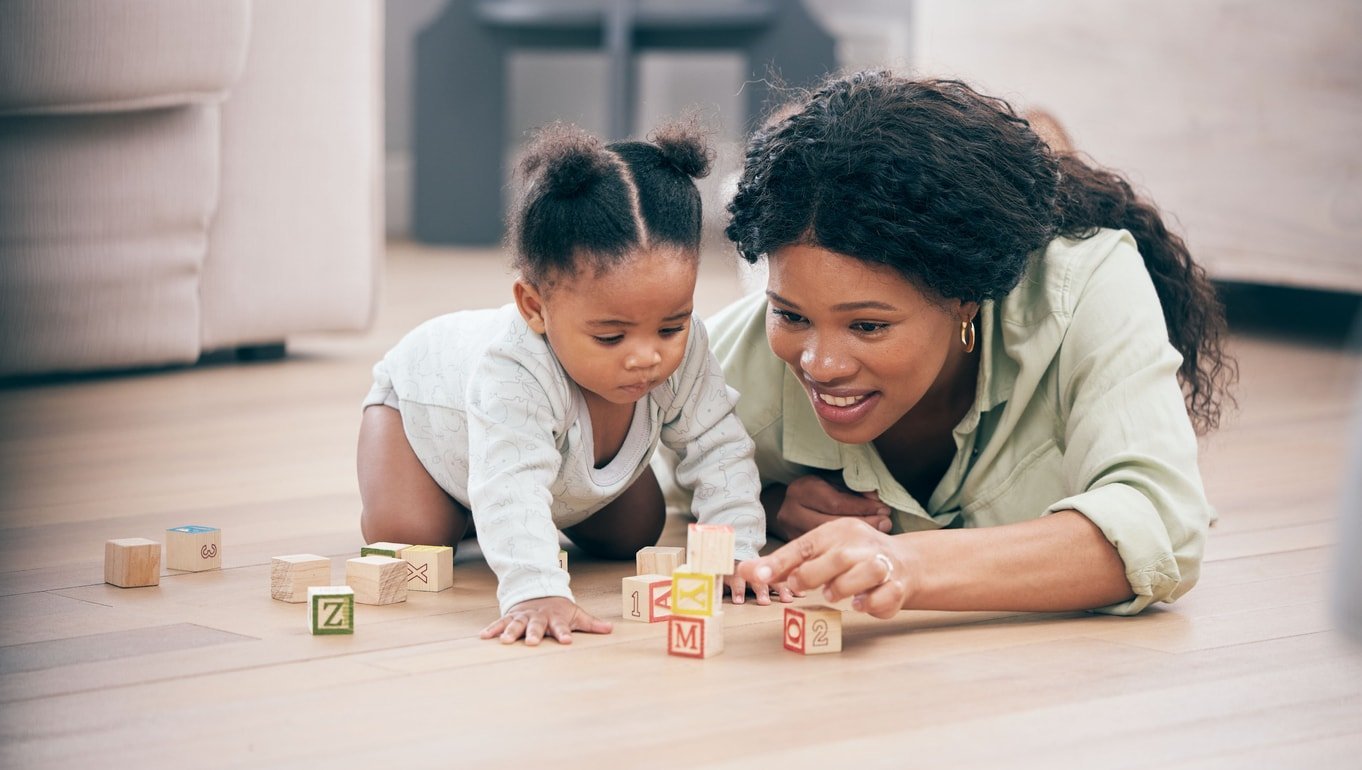 Blocos de construção de bebês, mães e brinquedos para o desenvolvimento do conhecimento infantil no chão da sala.  Casa de família, ensino e mãe com criança aprendendo e ajudando com felicidade e um sorriso com amor