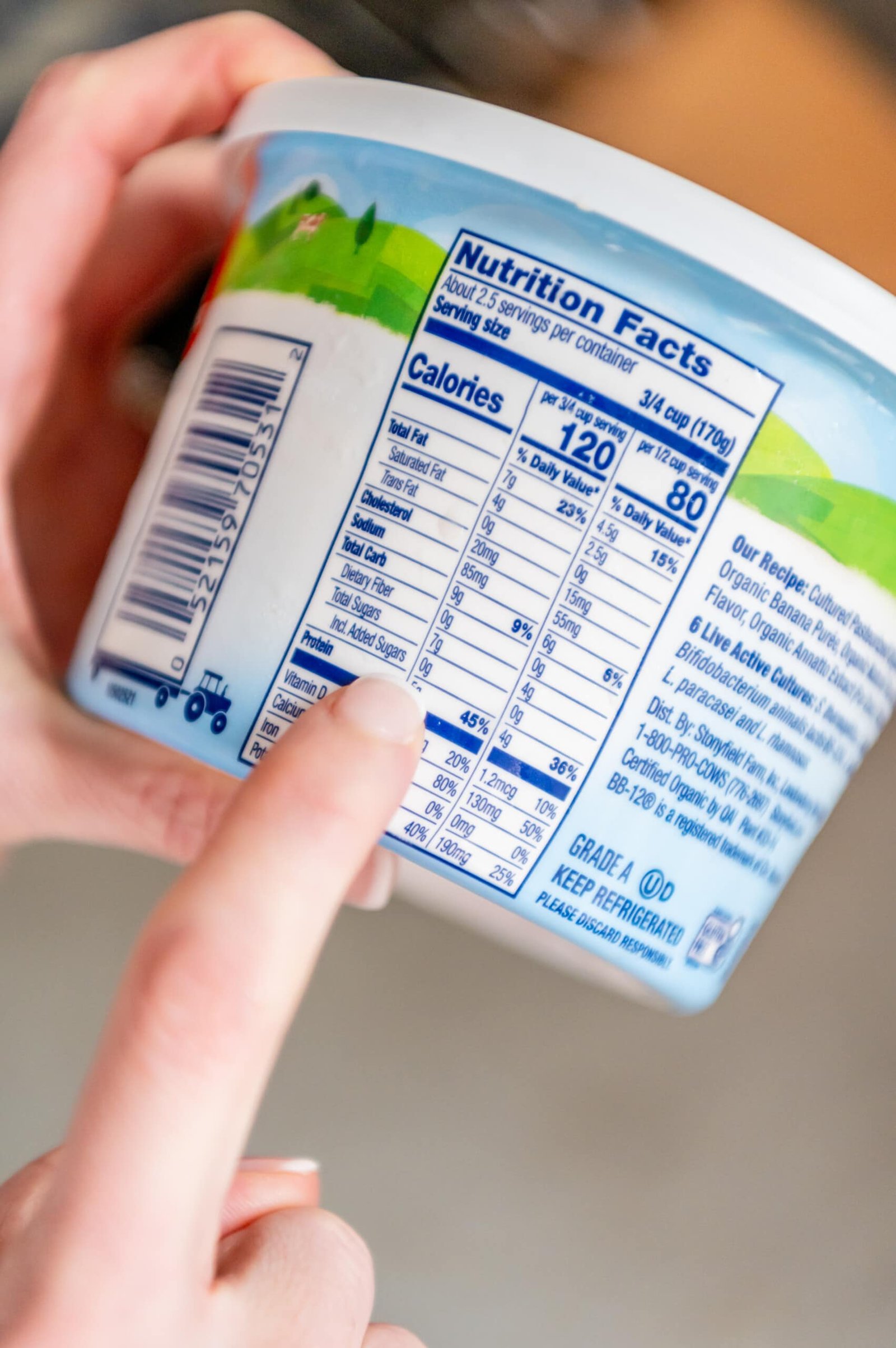 Dedo apontando para informações nutricionais e mostrando que o novo iogurte Yobaby da Stonyfield não contém açúcares adicionados