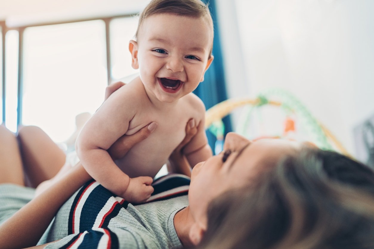 Mãe brincando com seu bebê deitado no chão