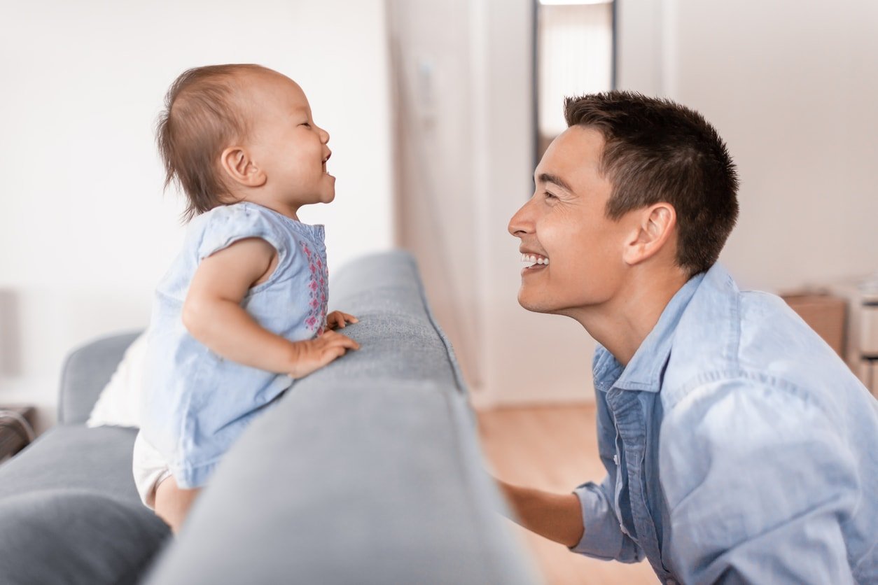 Pai e filha felizes brincando de esconde-esconde no sofá.