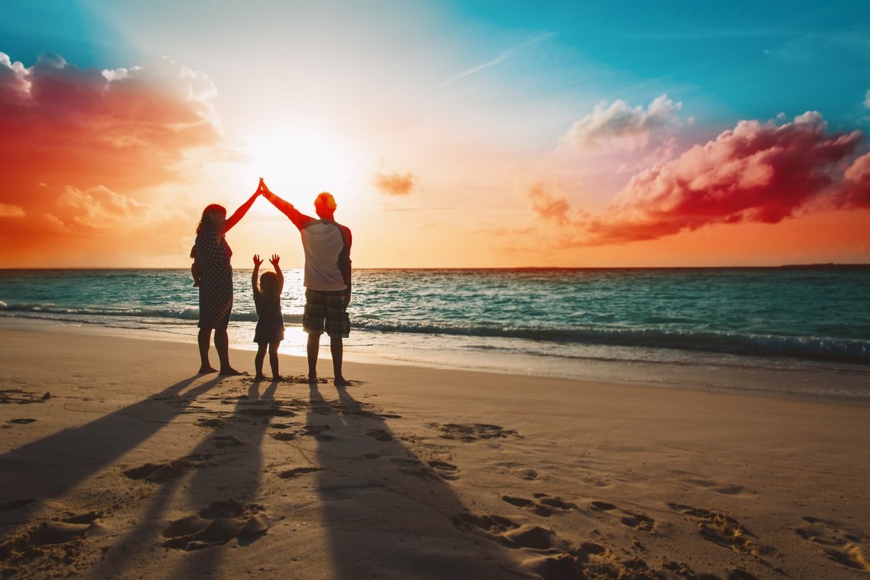 família feliz com crianças brincam na praia tropical do pôr do sol