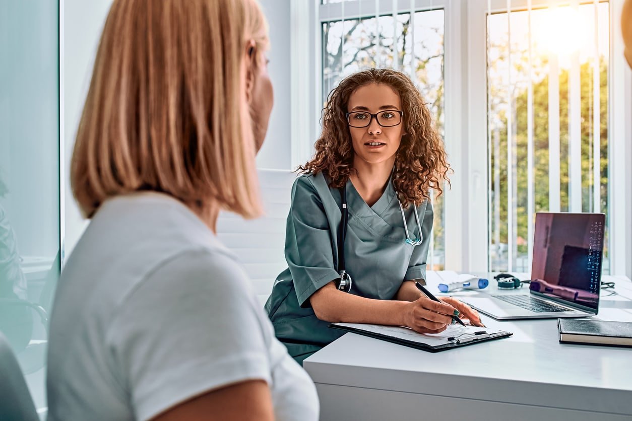 Mulher médica vestida com traje médico falando no escritório.  Recepção e consulta com médico.