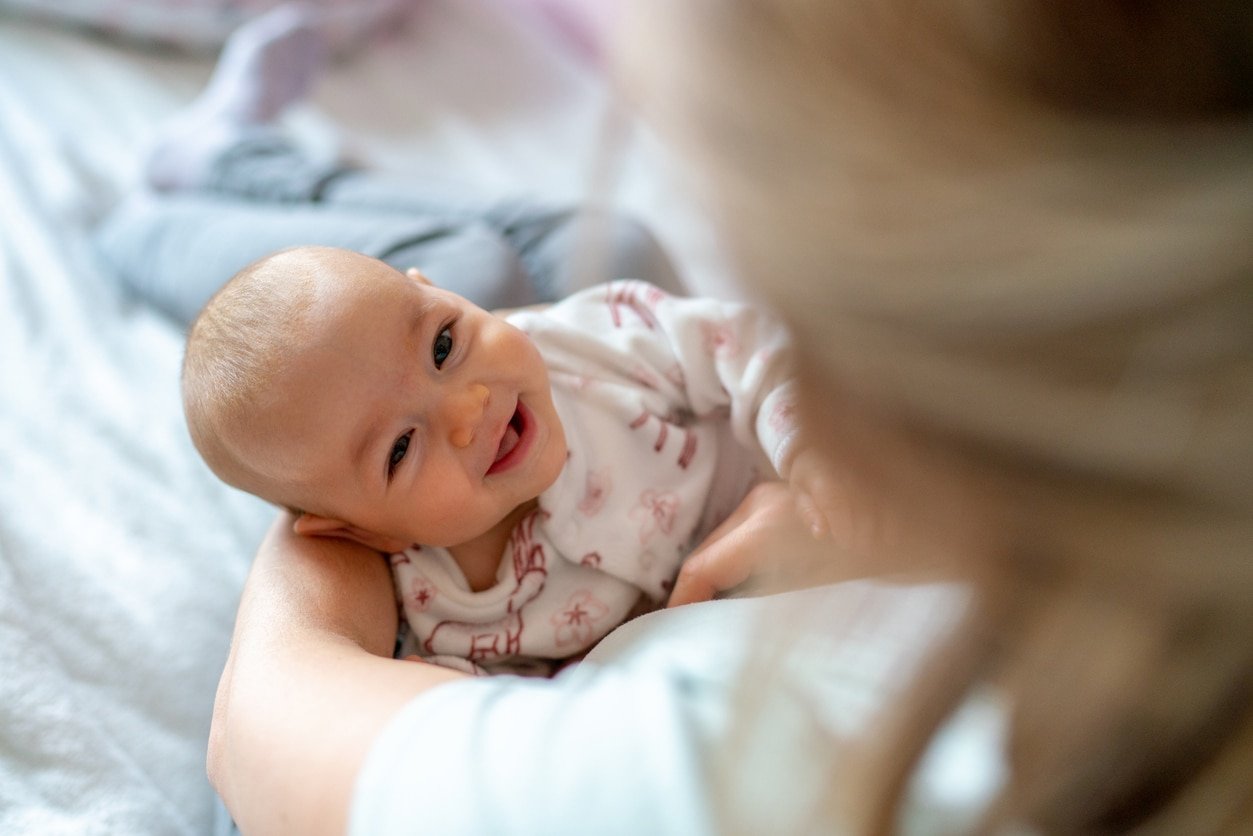 Mãe carregando sua filha sorridente em casa